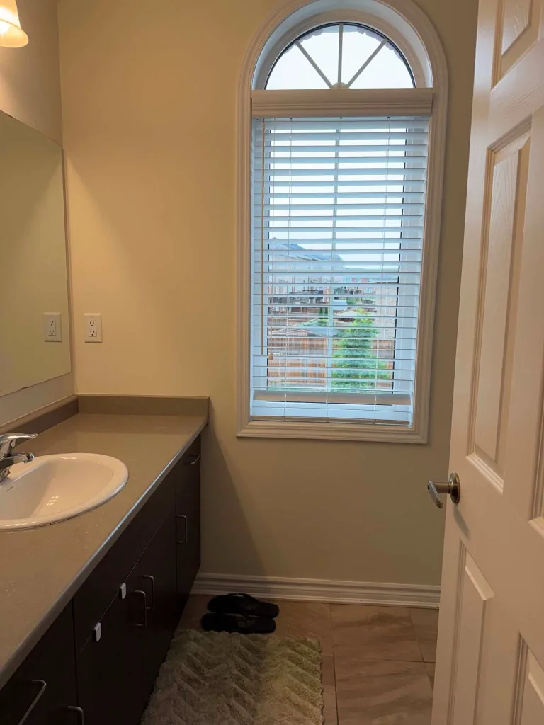 Bright bathroom with dark vanity and arched window after cleaning