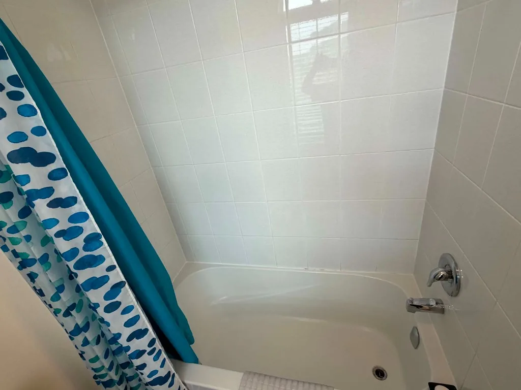 Freshly cleaned bathtub with blue patterned shower curtain