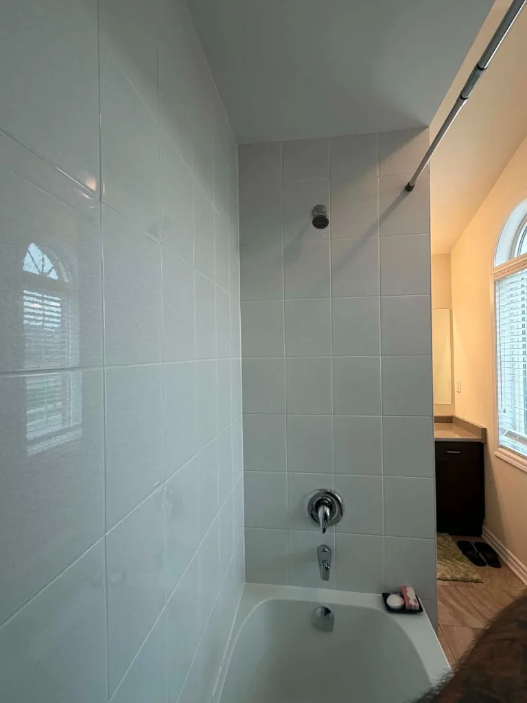 Glossy tiled bathtub and shower enclosure after deep cleaning