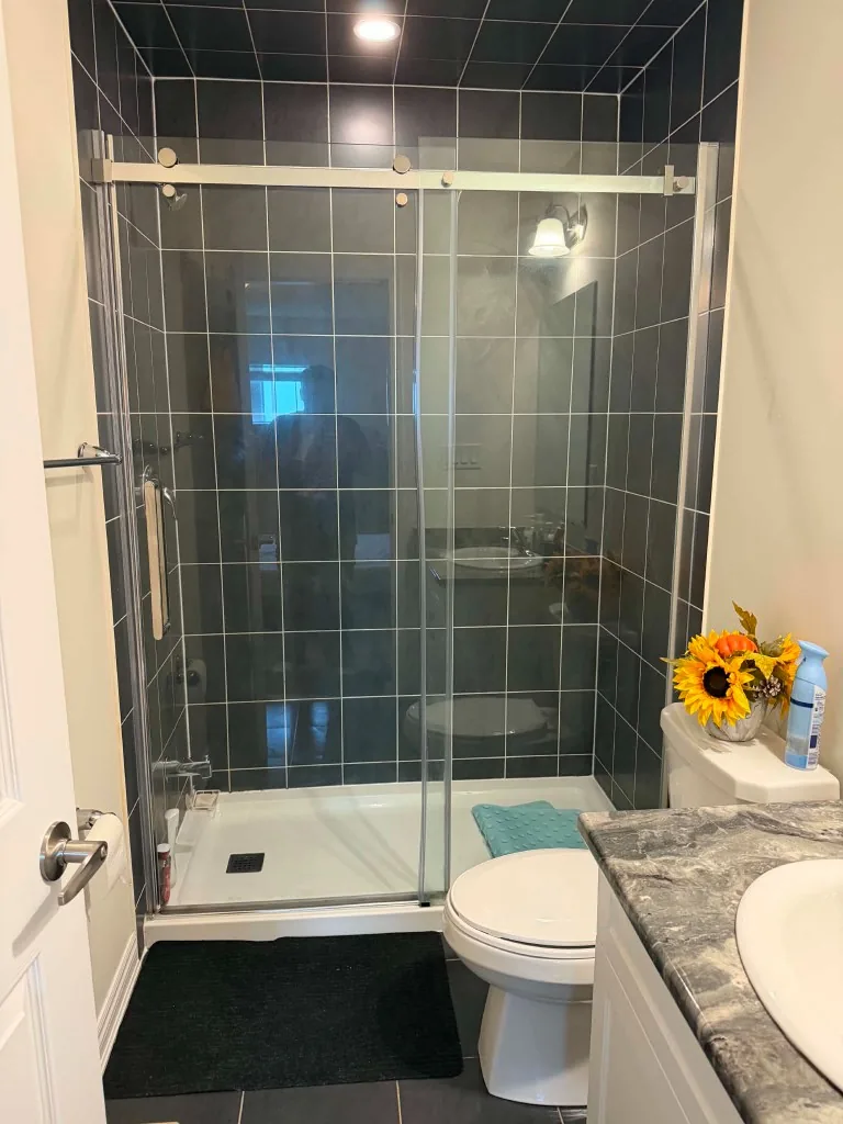 Modern glass shower with dark tile after professional cleaning